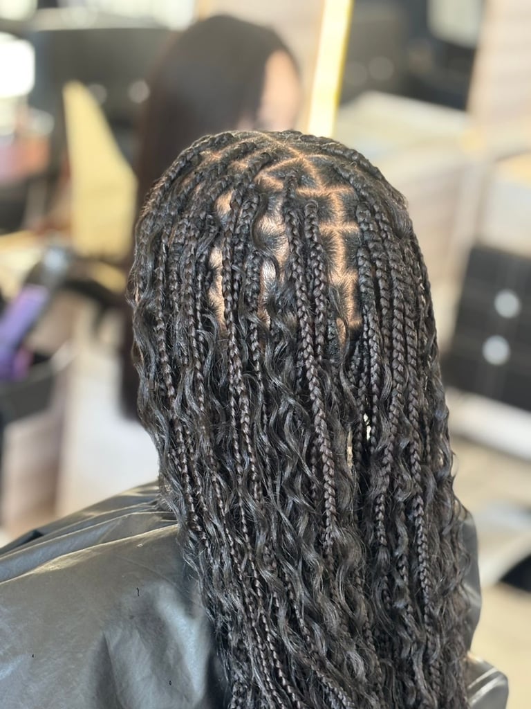 Close-up view of Black braided hairstyle with intricate patterns, photographed from behind in a salon setting